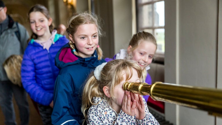 Children look through a telescope in the West Wing at Seaton Delaval Hall, Northumberland